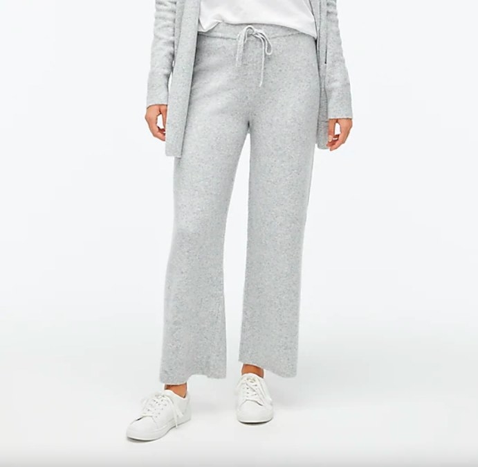 Model wearing gray pants, white top, gray sweater and white sneakers