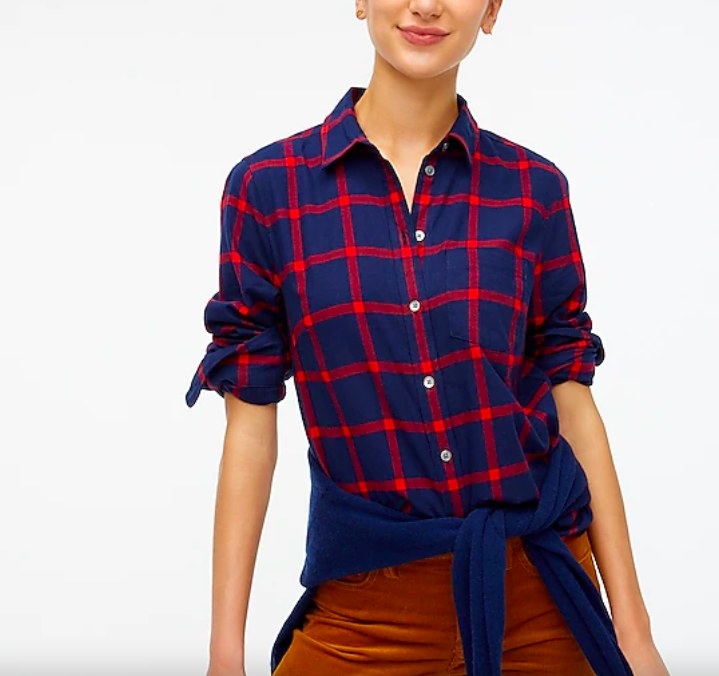 Model wearing red and navy flannel shirt, blue sweater around the waist and brown pants