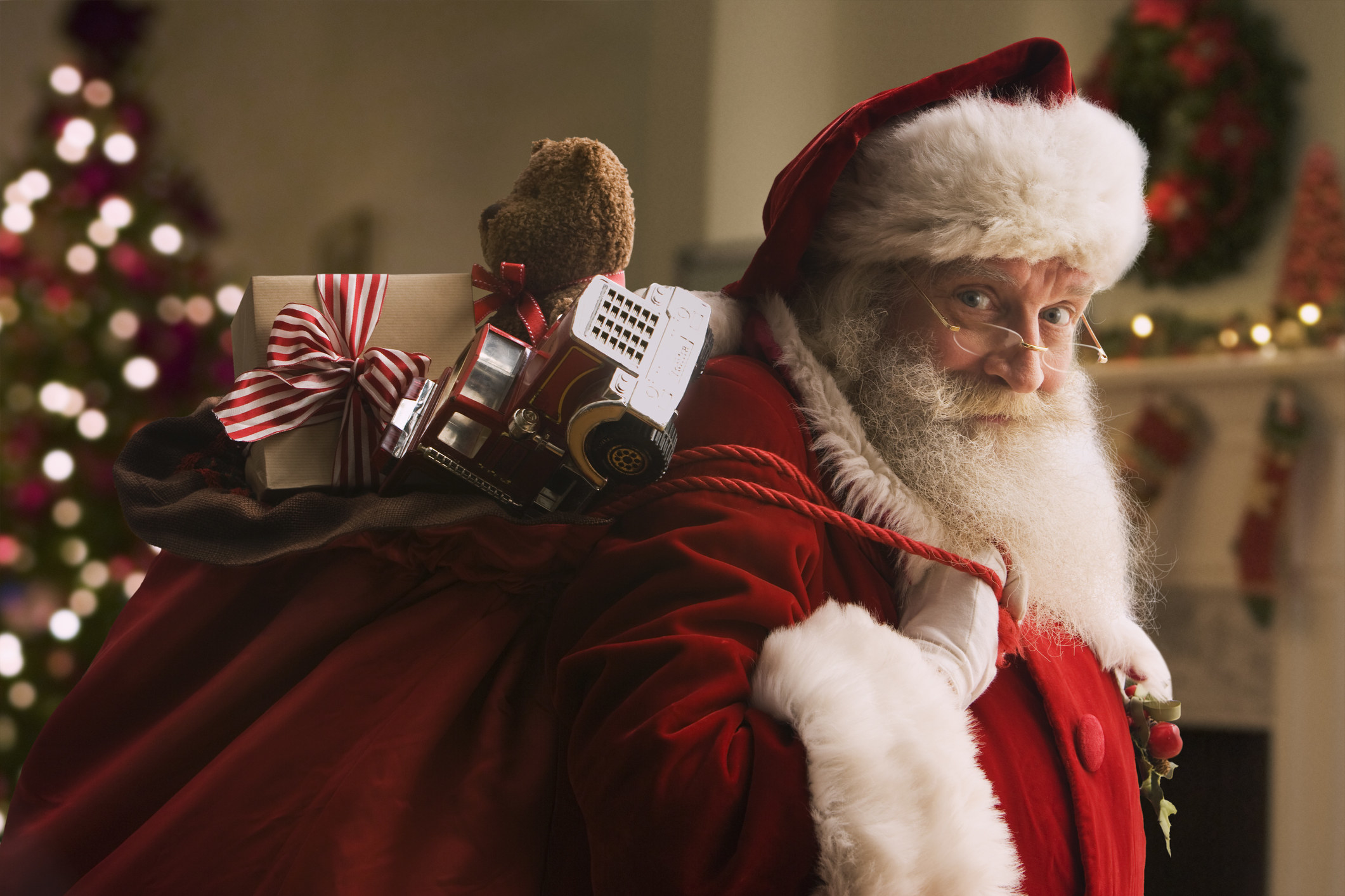 Santa smirking as he carries a bag full of toys