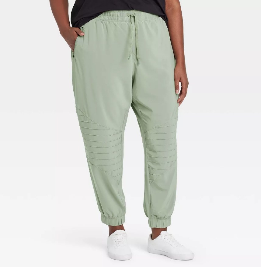 A model wearing a pair of mid-rise stretch woven moto pants in sage