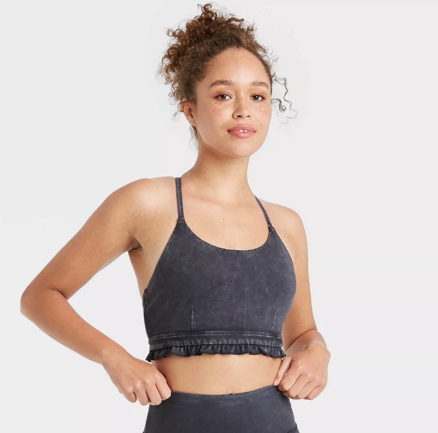 A model wearing a black wash strappy back sports bra with ruffles