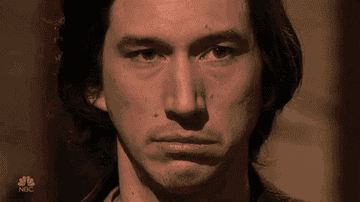 Kenan Thompson looks over at Adam Driver with wide eyes as Adam Driver glares back in