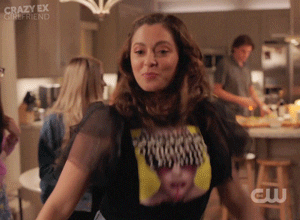 Rachel Bloom as Rebecca Bunch waves her hands around and pulls them up to her chest as she dances in