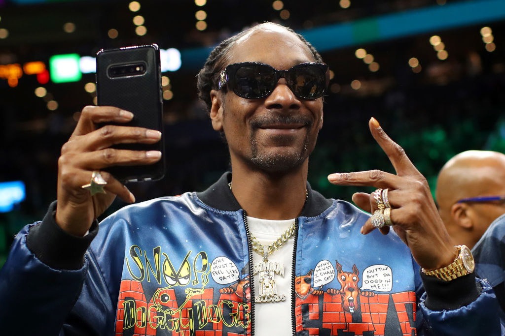 Snoop holding up a phone and smiling