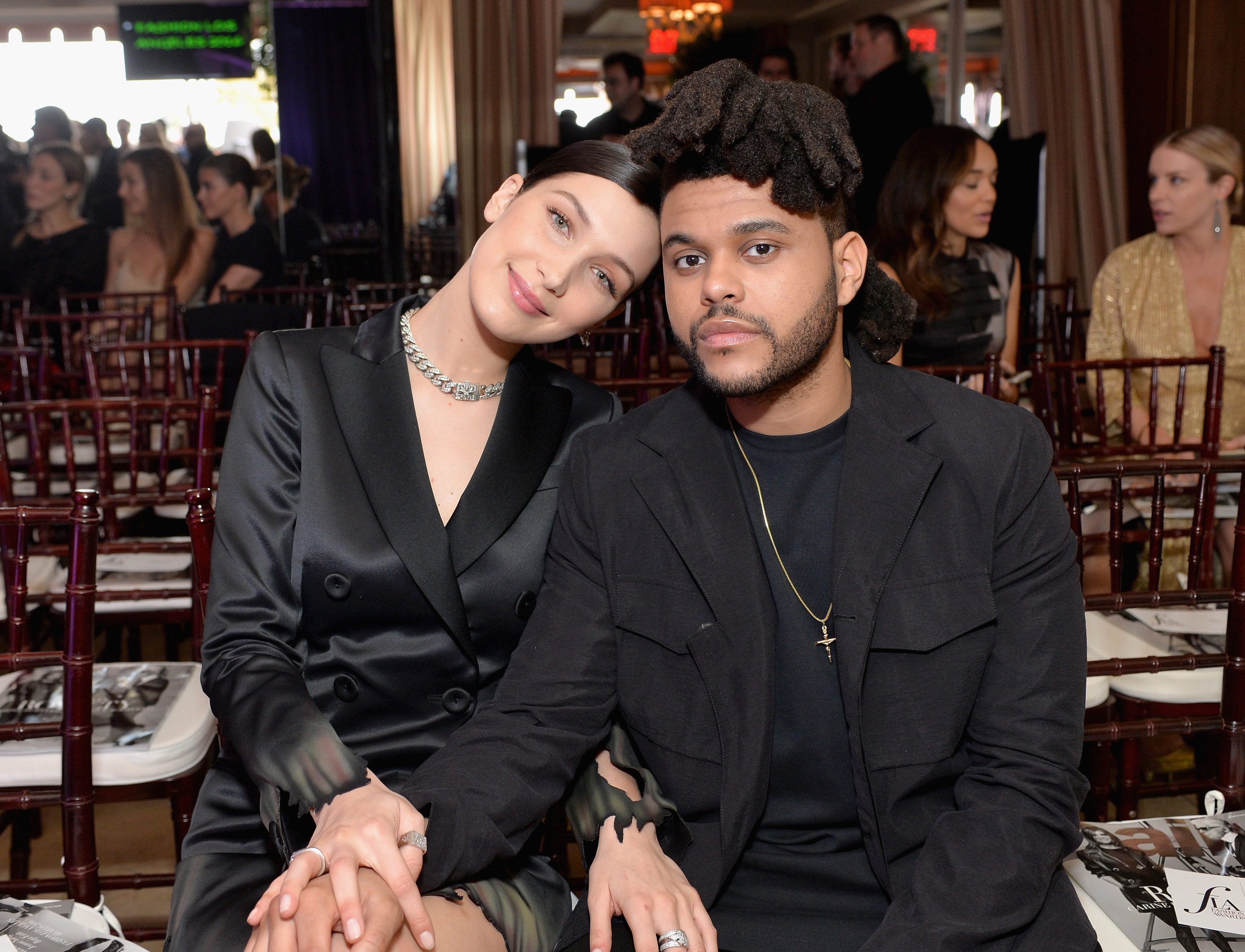 Bella and the Weeknd sitting together and touching each other&#x27;s legs at a fashion show