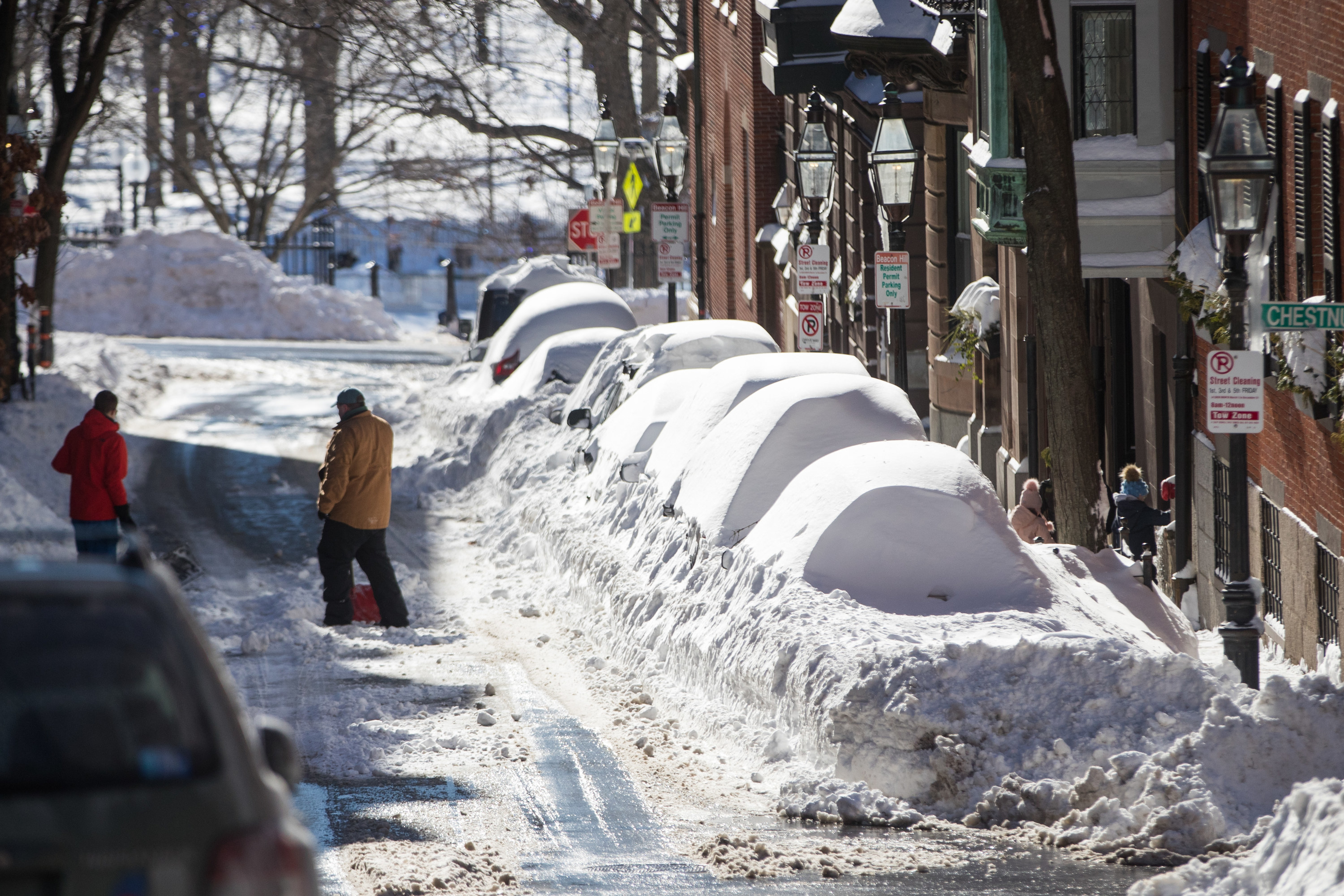 Two people clear snow on a street