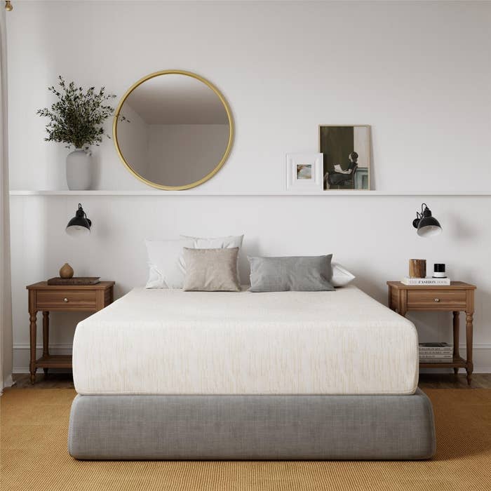 Full size memory foam mattress with pillows next to two wooden nightstands