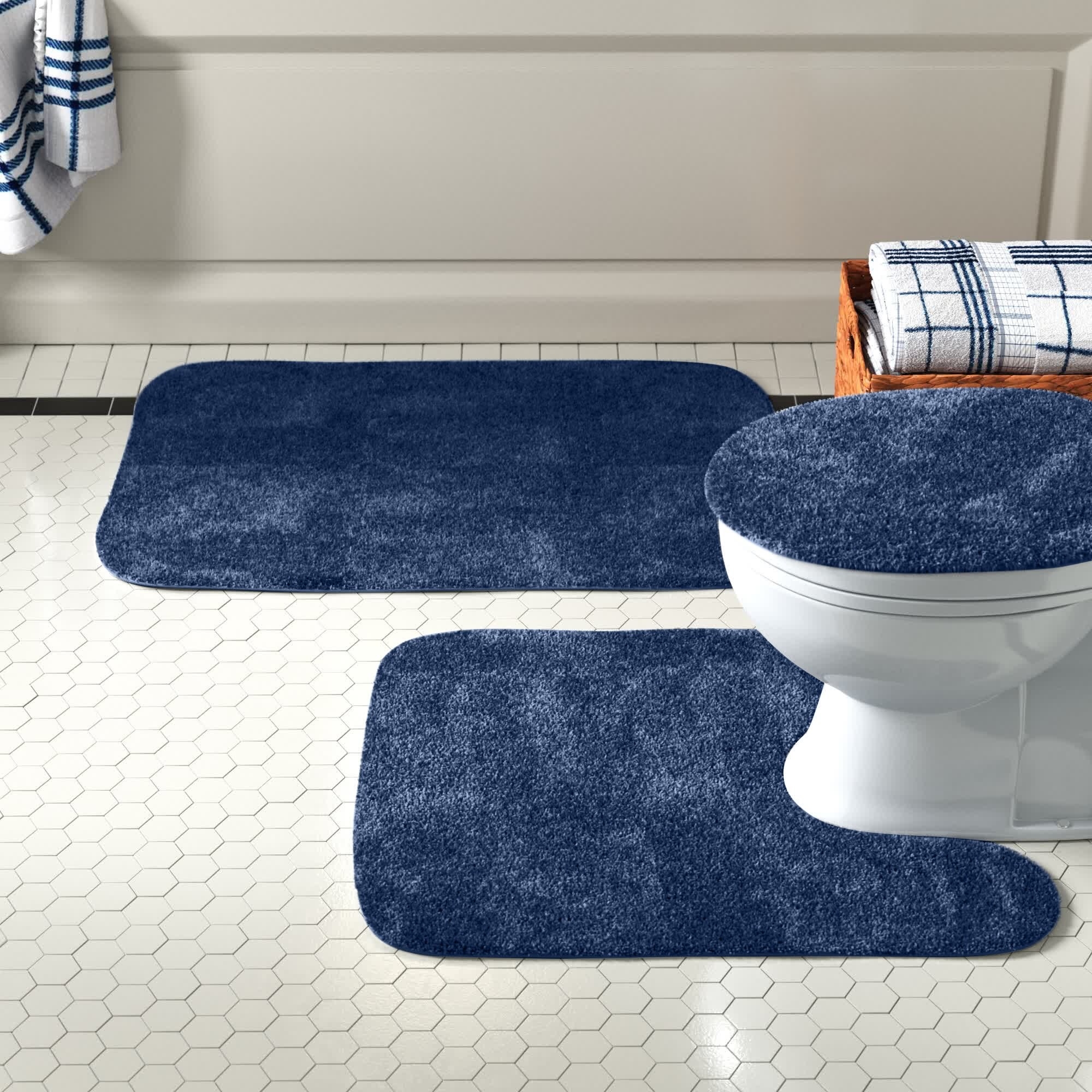 Blue bath rug set underneath toilet, on seat and by shower