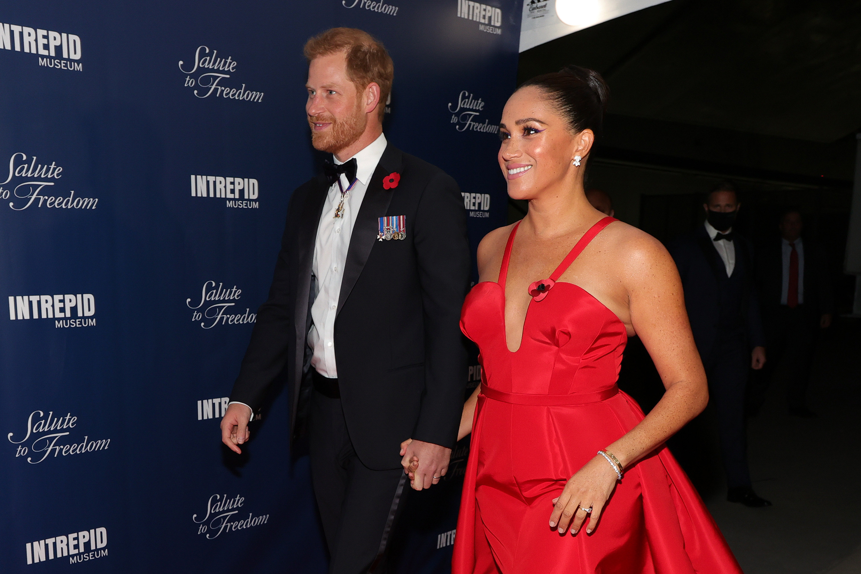 Harry and Markle walk during a step-and-repeat