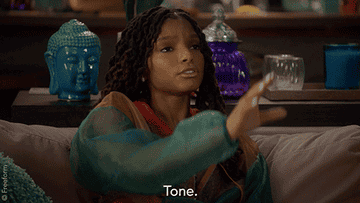 A woman puts her hand up to someone off camera and says tone in a stern way