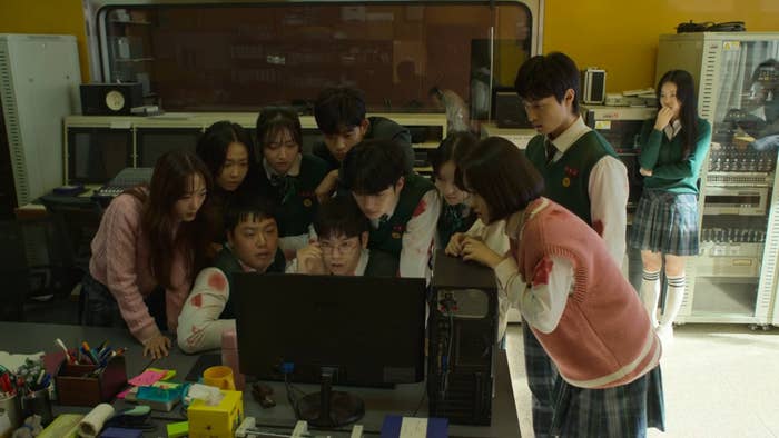 Students with bloody clothes huddle around a computer