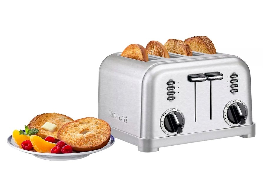 Toaster with bread in it next to a plate with toasted bagel and fruit