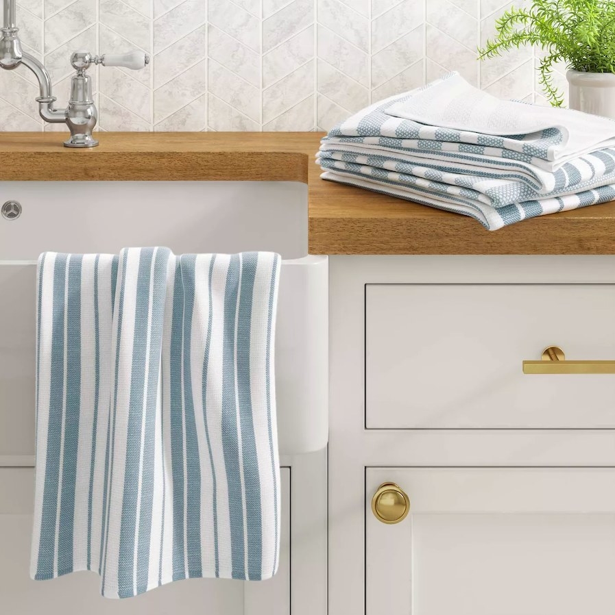 Striped white and blue dish towel hanging off a kitchen sink
