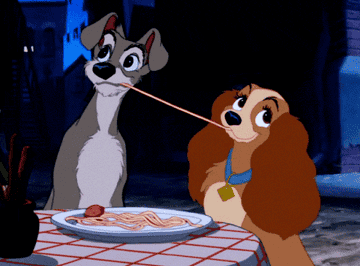 Gif from Lady And The Tramp of two dogs sharing a string of spaghetti