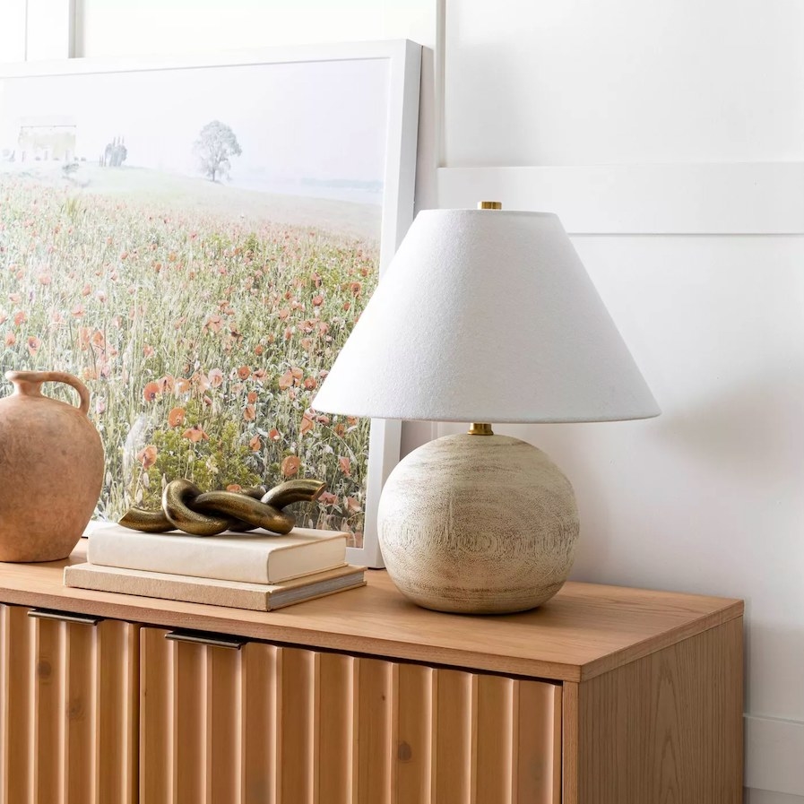Table lamp shown on a console with accessories and a piece of art