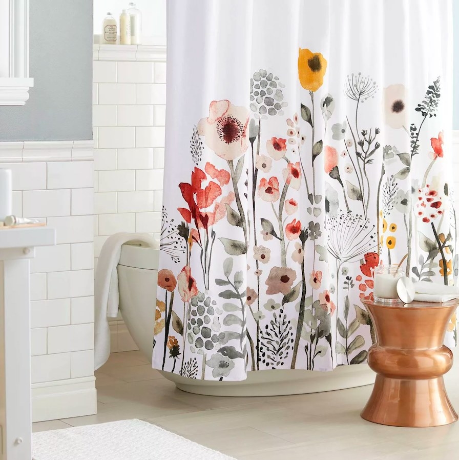 Shower curtain shown on a tub next to a copper stool