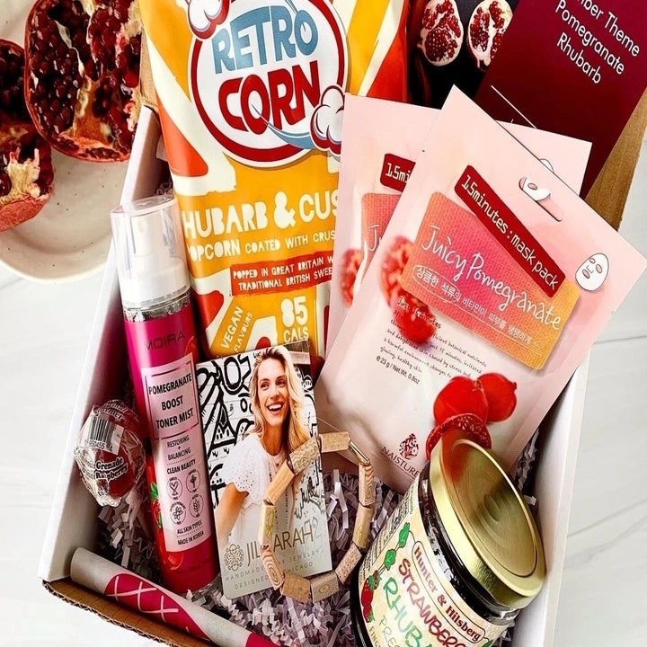 A pomegranate and rhubarb-themed box filled with popcorn, jam, and body products