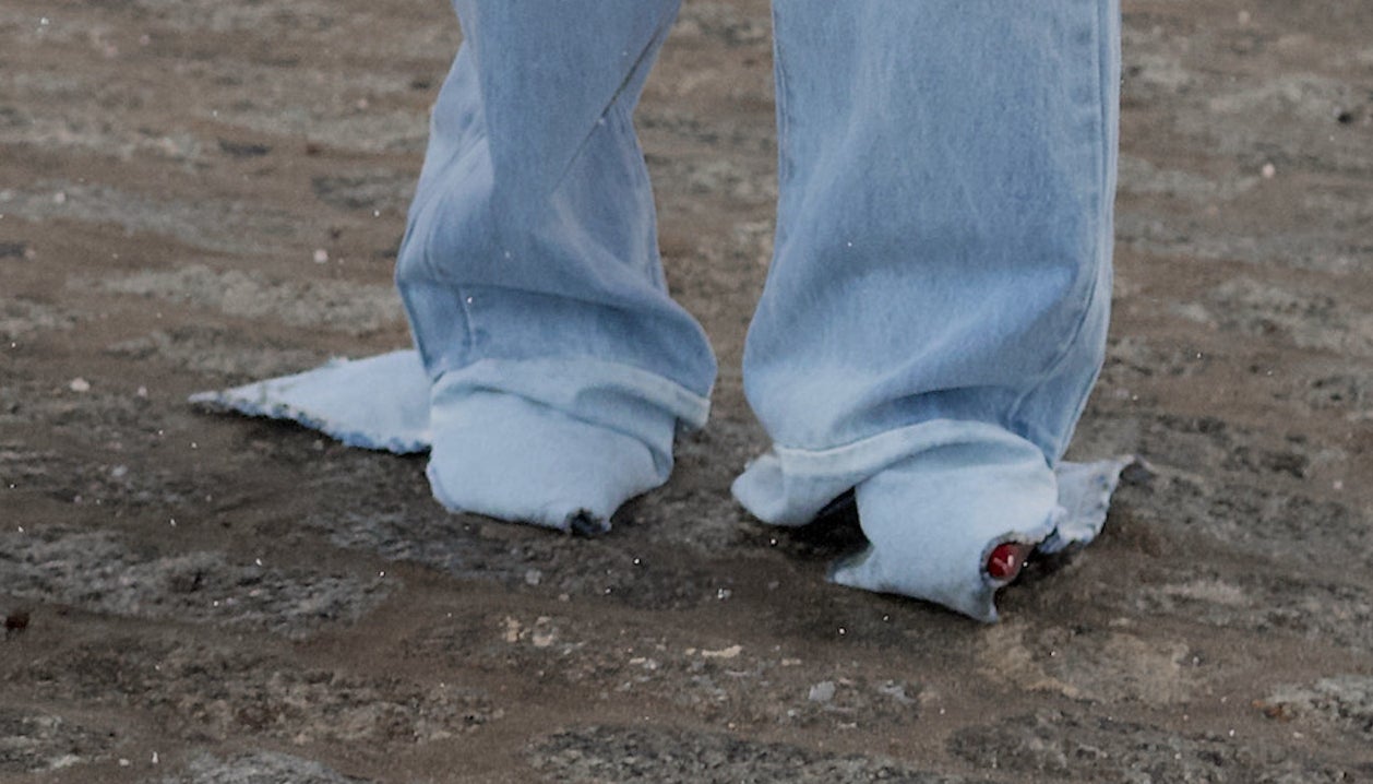 A closeup of Rihanna's jeans which are oversized and ripped at the bottom and completely covering her feet