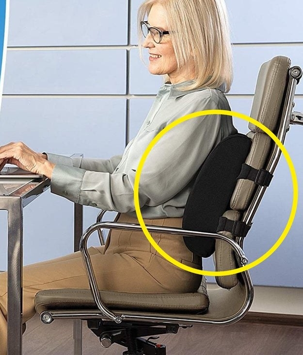 A person sitting at their desk with the lumbar support cushion attached to their chair