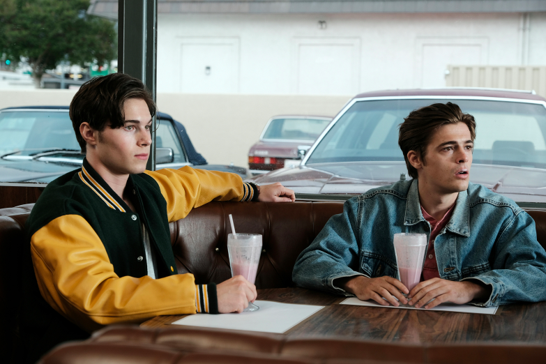 A young Cal and Derek sitting in a booth drinking milkshakes