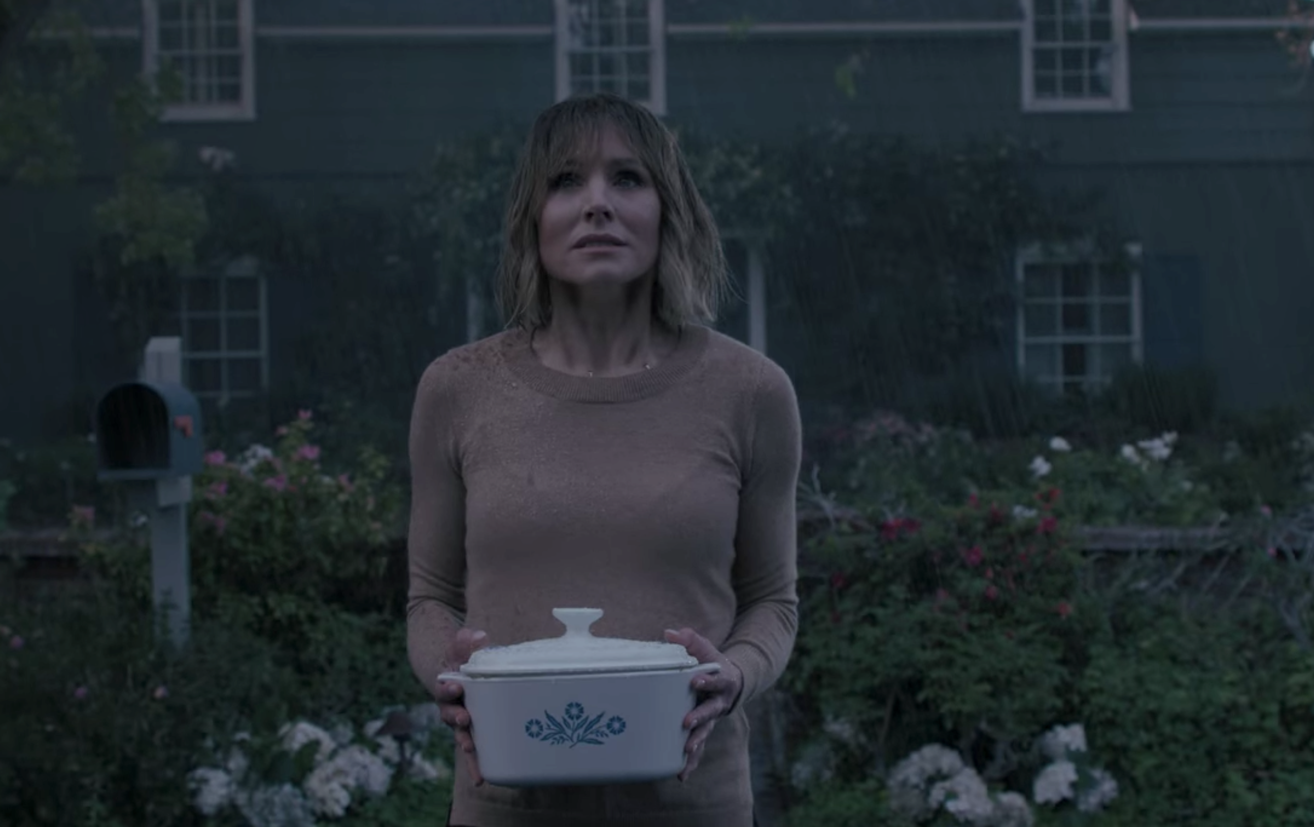 Kristen&#x27;s character holding a dish while standing in the rain