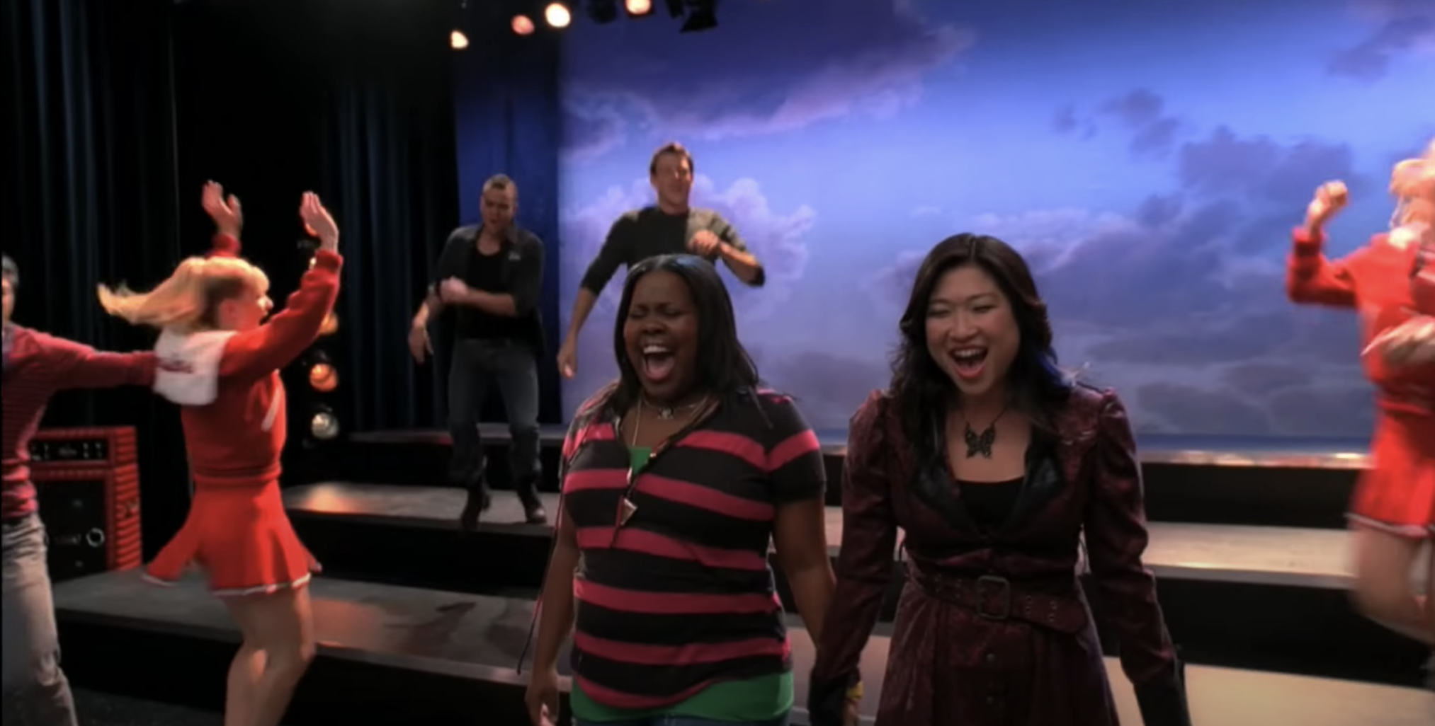 Mercedes and Tina singing onstage while the New Directions dance around them