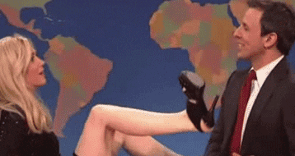 Kristen Wiig scoots on a rolling chair toward Seth Meyers, with her legs up and open, on SNL