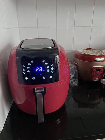 reviewer image of red compact air fryer in corner of kitchen counter
