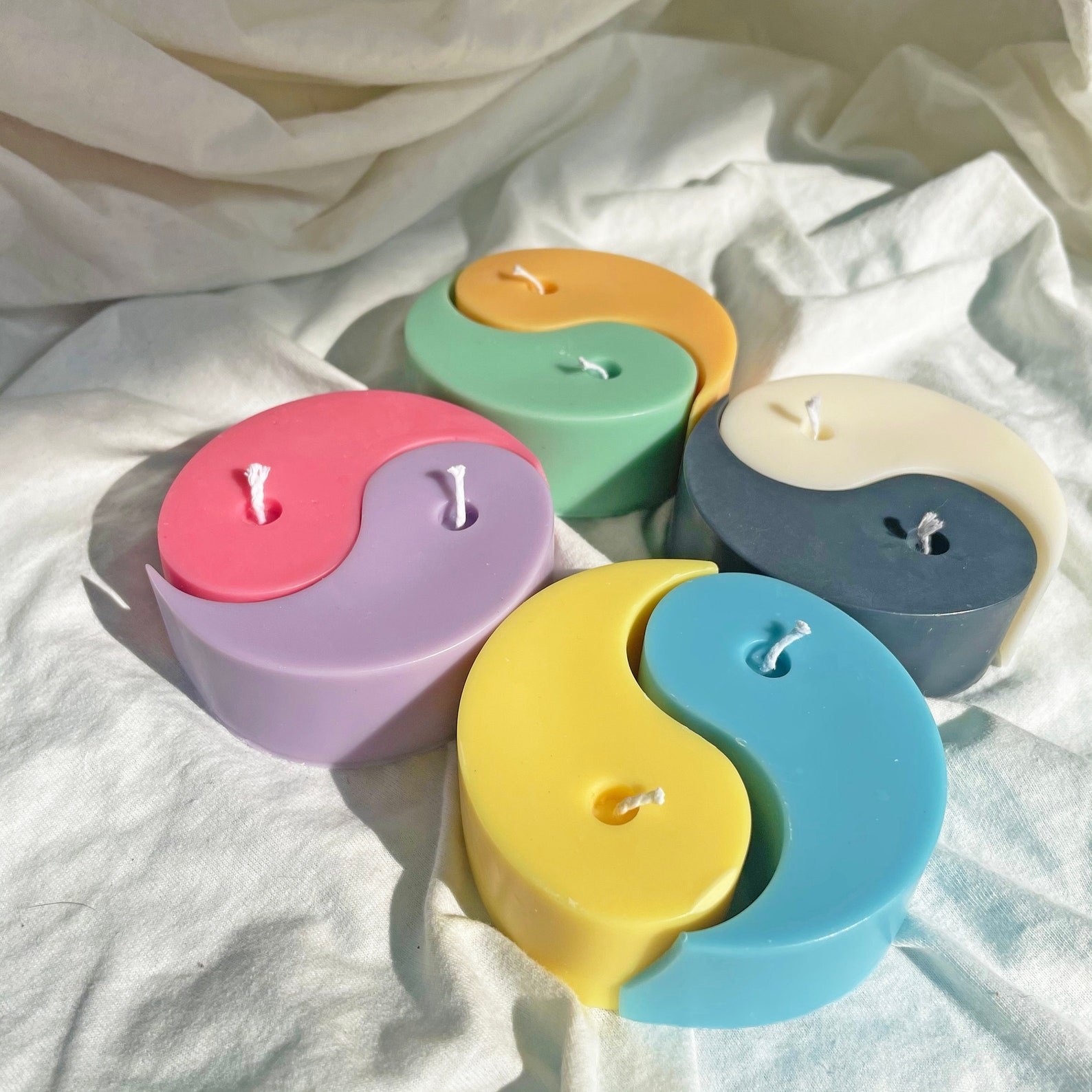several yin yang candles on a white cloth