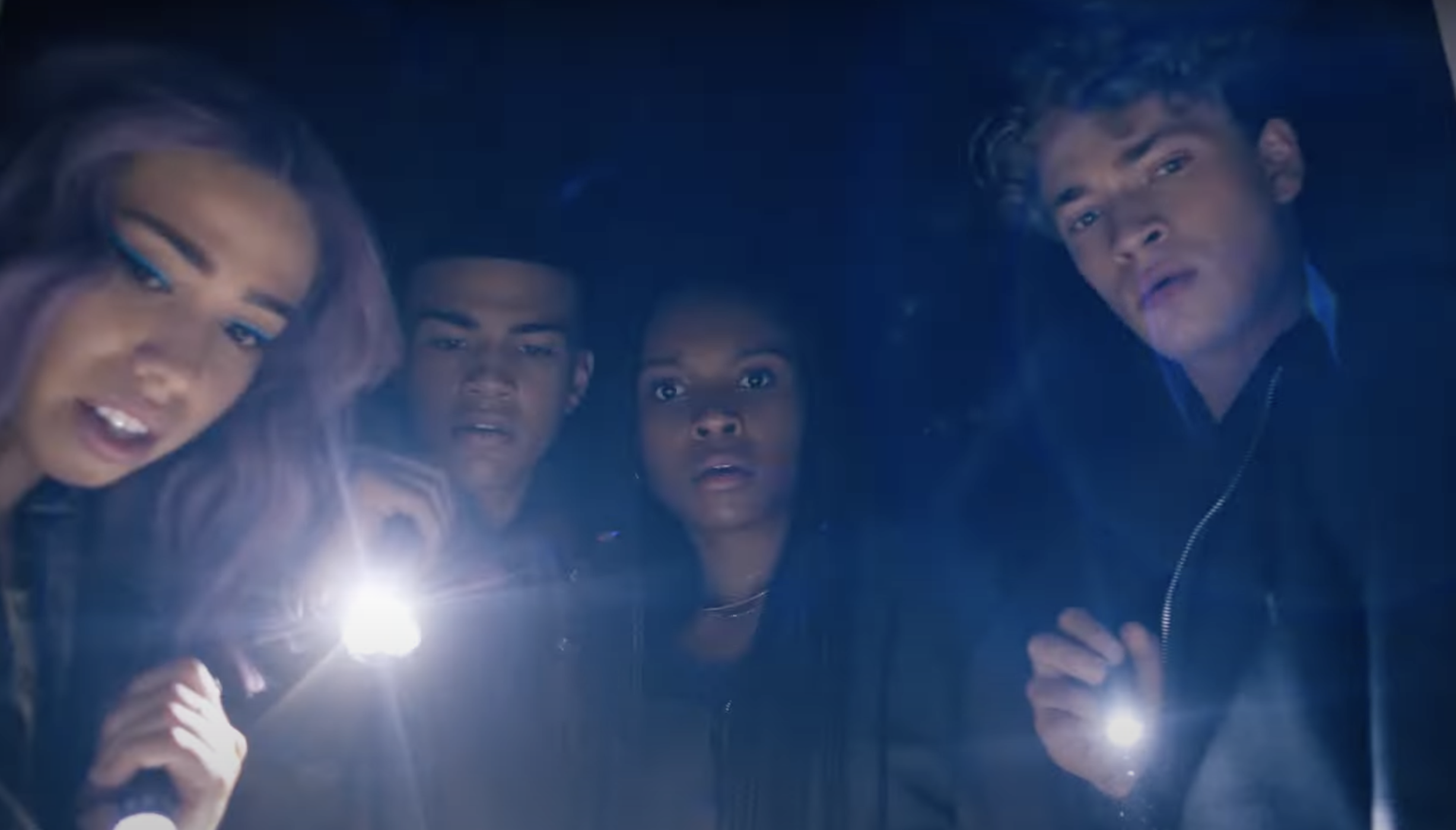 Kaci Walfal as Naomi stands around with friends holding flashlights and looking at something