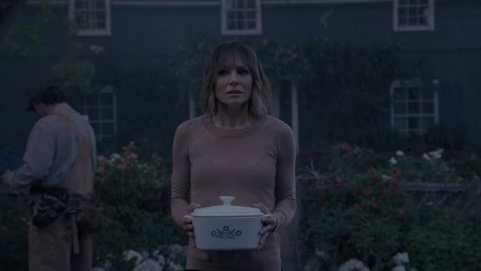 Kristen Bell in The Woman In The House Across The Street From The Girl In The Window standing in the rain holding a casserole dish looking scared