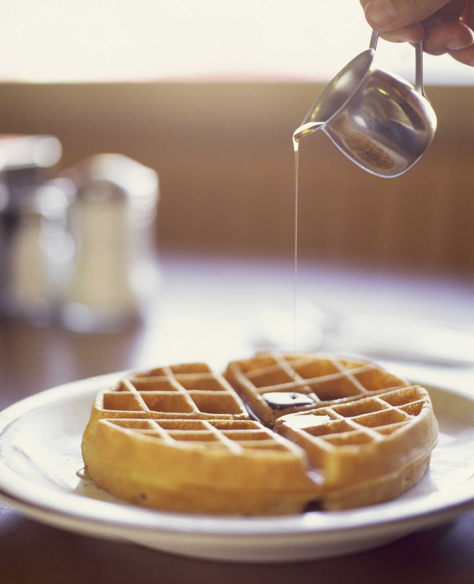 Pouring syrup on waffle.