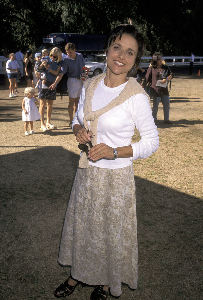 julia appears to be at a horse show dress in preppy styled sweater and a floral-print skirt