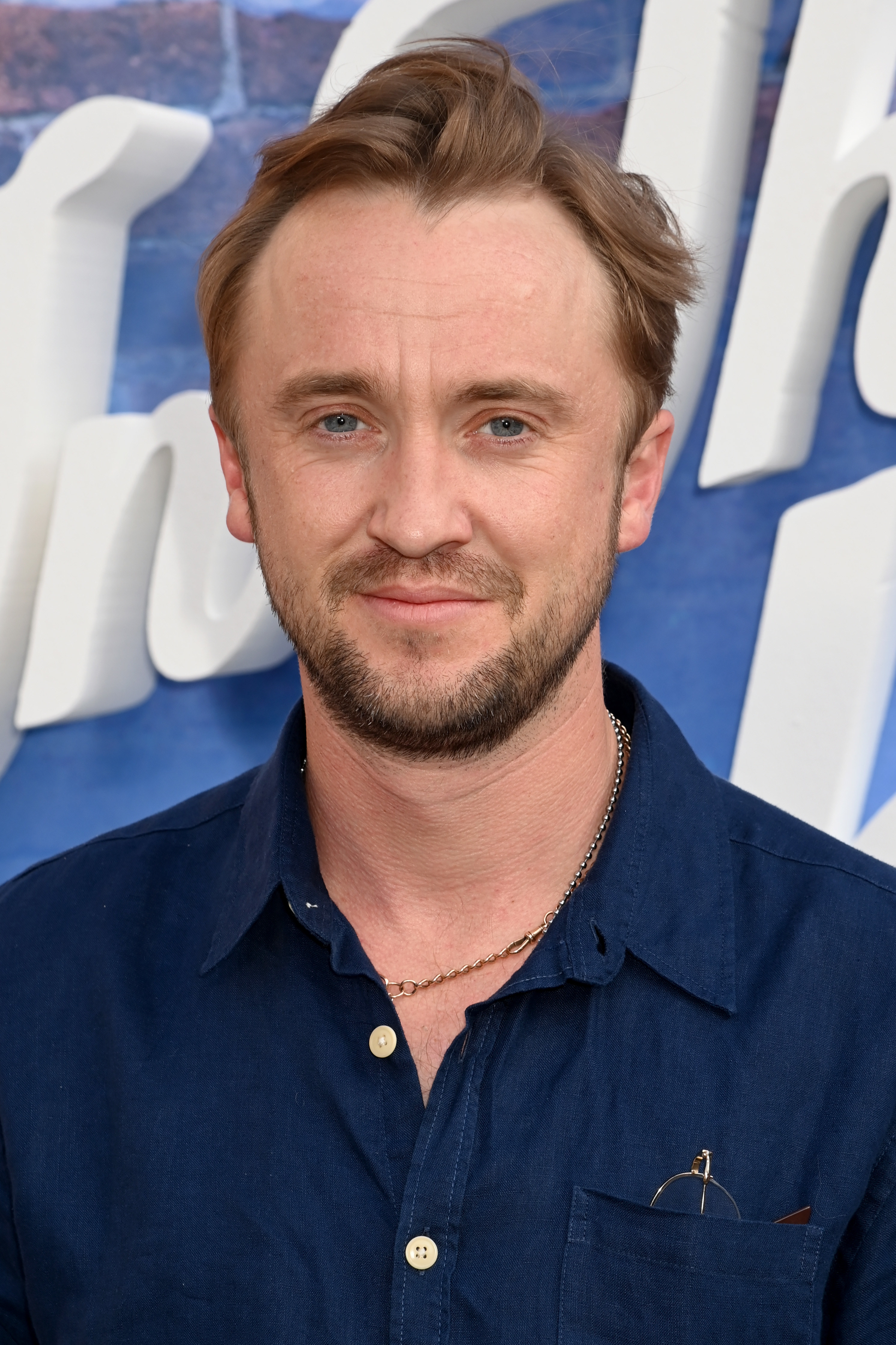 Tom Felton at an event with a pair of glasses in his front shirt pocket