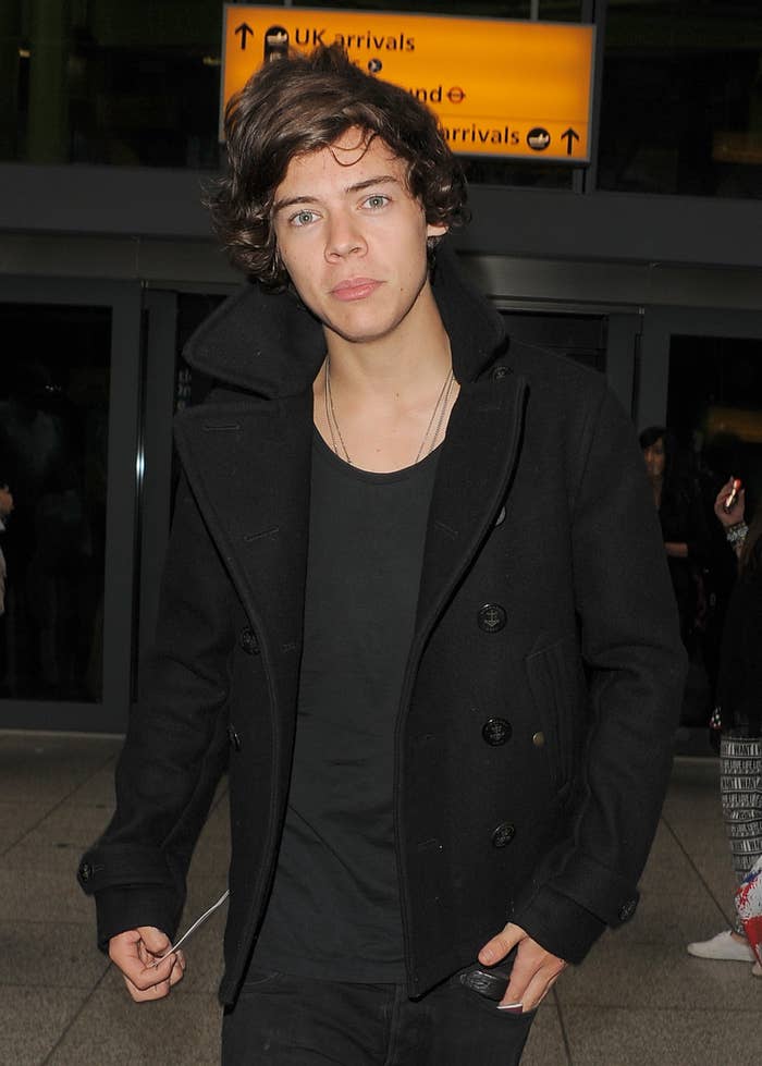 harry walking out of a concert venue in a t-shirt and pea coat
