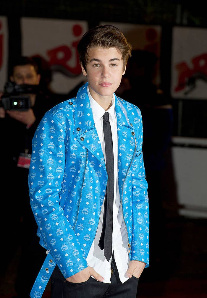 Justin is in a blue suit at Cannes film Festival wearing a dress shirt, tie, and an MCM leather jacket