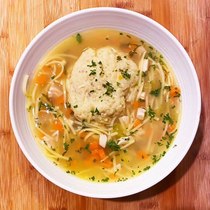 A bowl of homemade chicken noodle soup with a matzo ball.