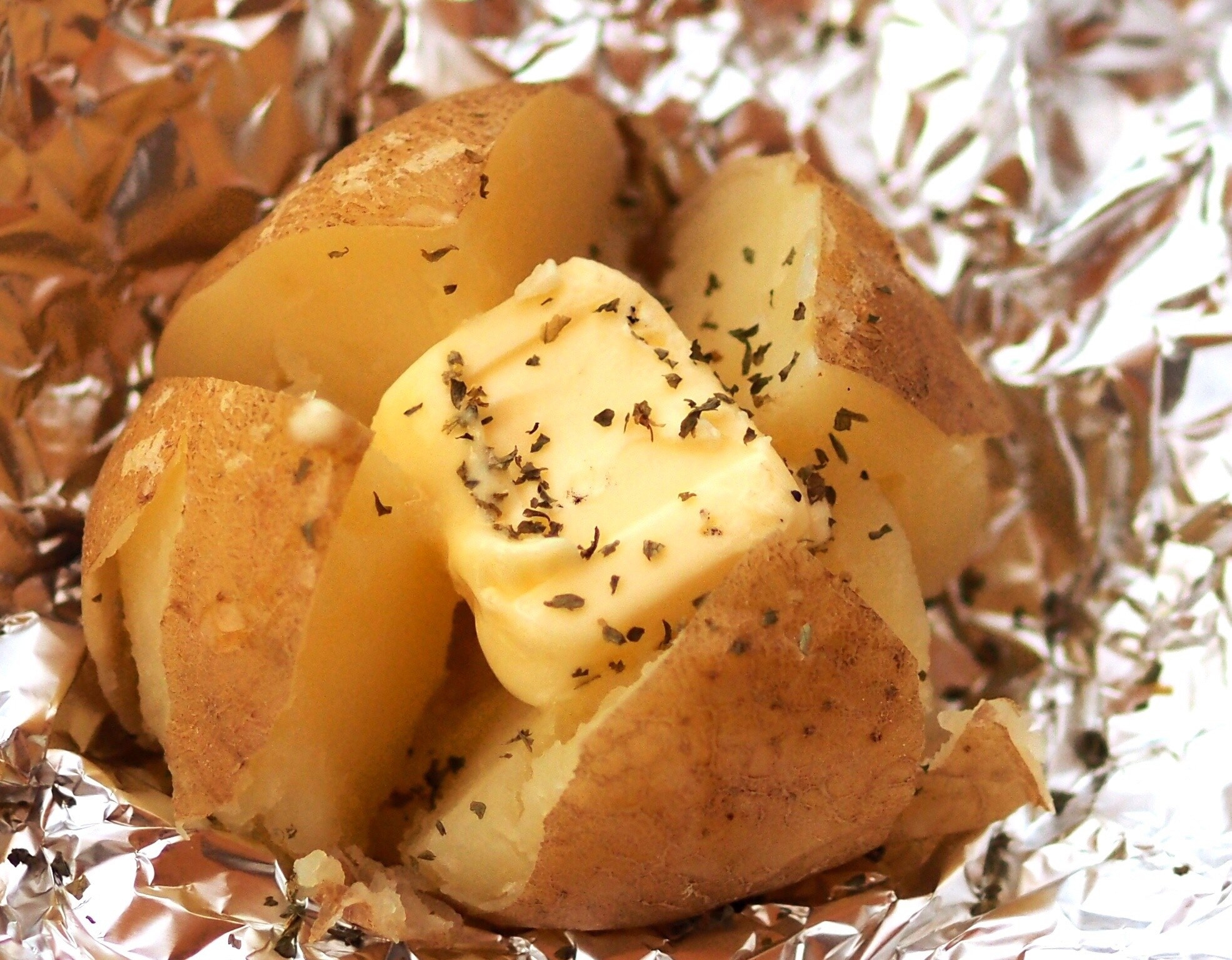Close-Up Of Baked Potato With Butter In Foil.