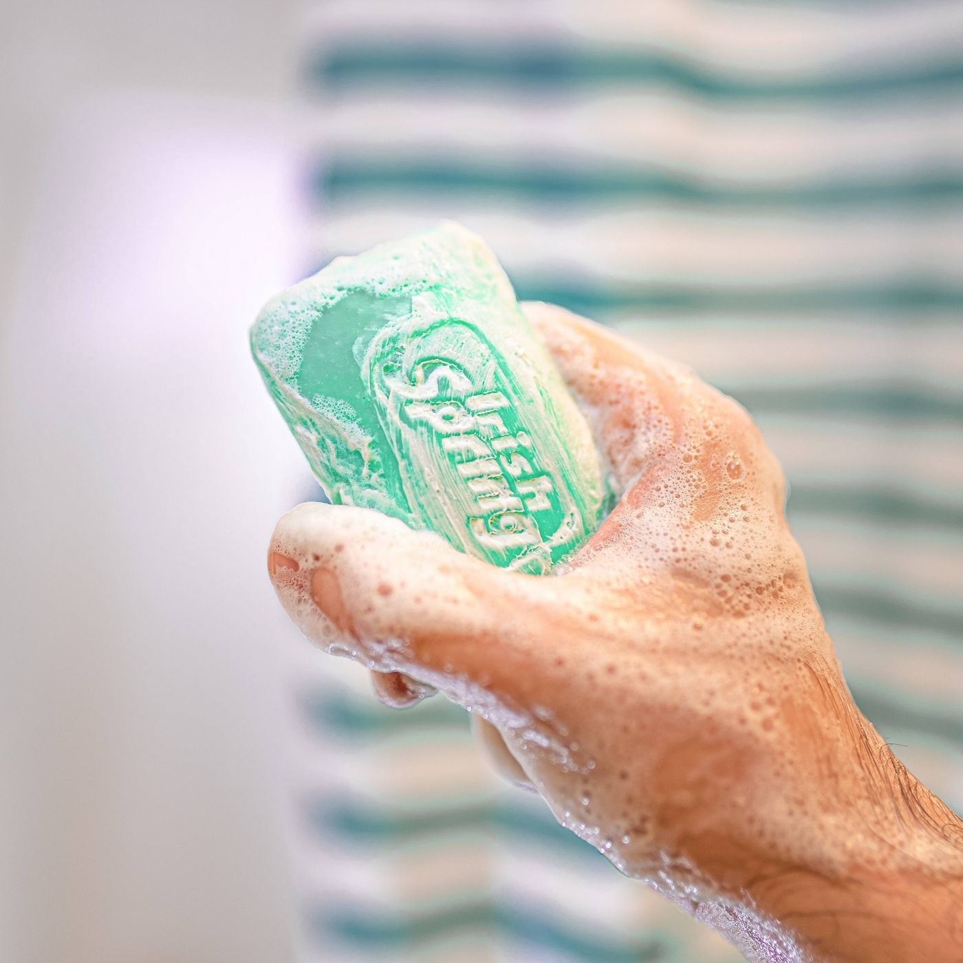 A image of a model holding a bar soap for body and hands