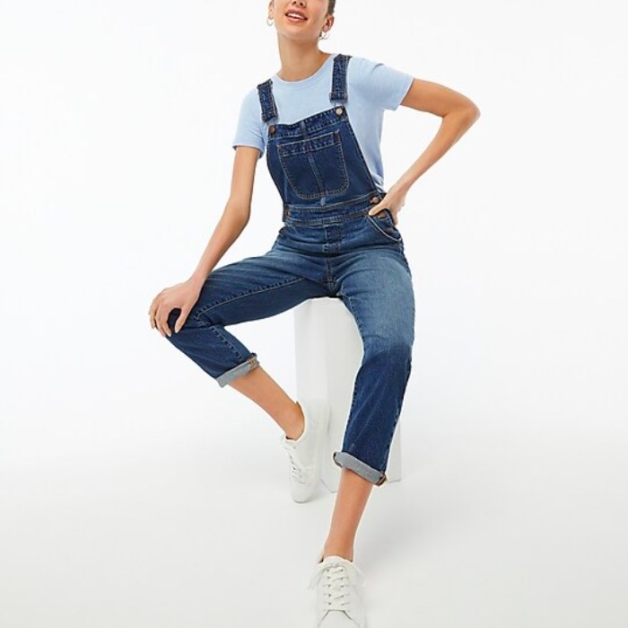 Model wearing overalls, blue tee and white sneakers