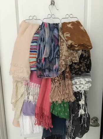 several scarfs hung up on the same organized hanger