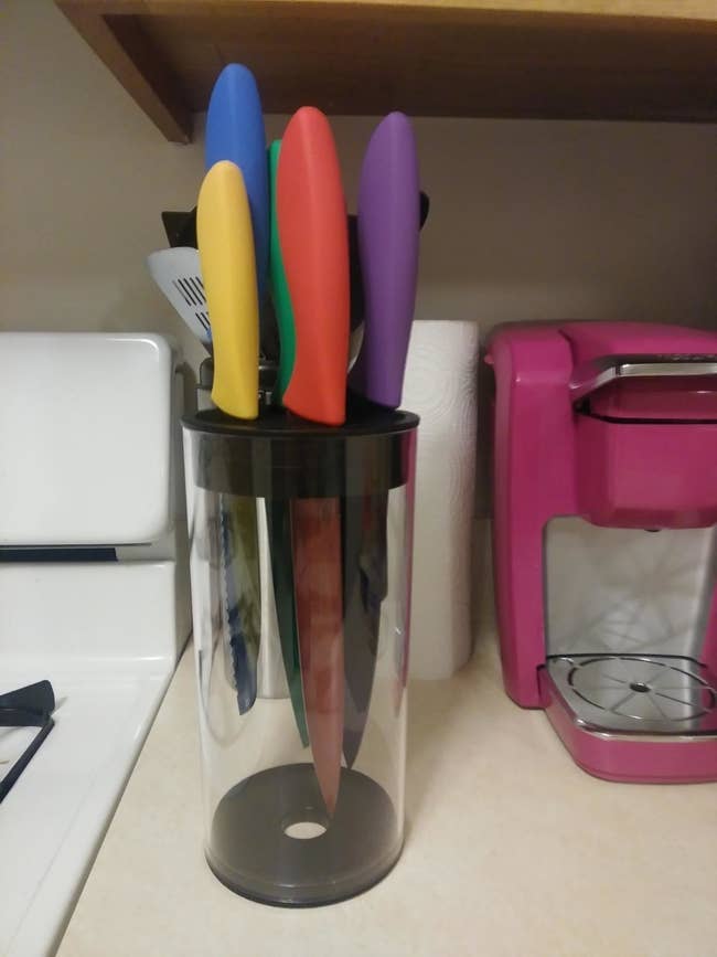 reviewer photo of the cylindrical transparent knife block holding a set of colorful knives