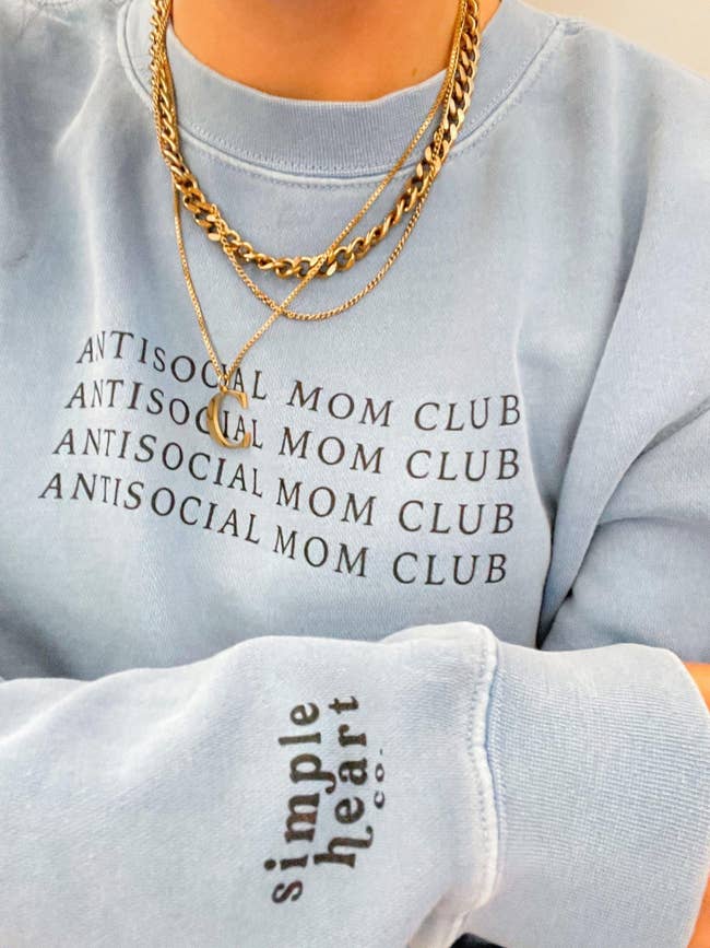a model in a light blue sweatshirt that says antisocial mom club on the chest four times