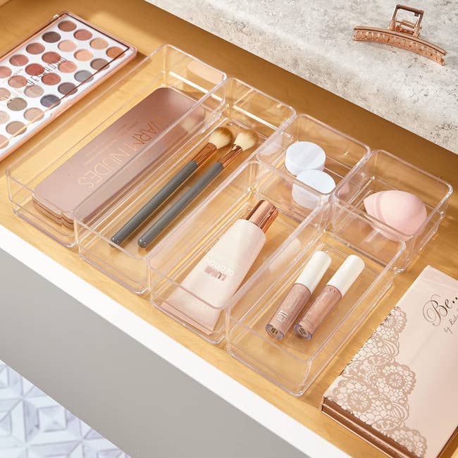 the clear bins inside of a drawer with beauty products in them