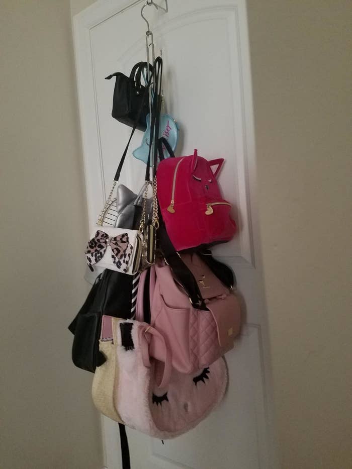 Reviewer photo of a collection of purses hanging on the bag organizer attached to the back of a closet door