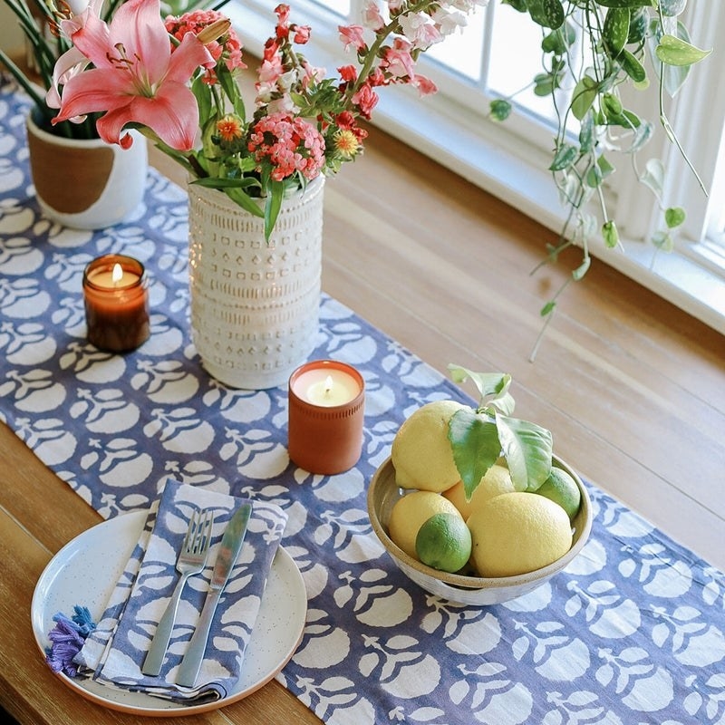 blue and white patterned table runner with bouquet of flowers in vase and fruit bowl on top