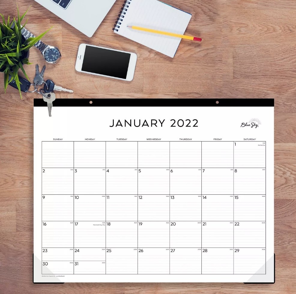 January 2022 white calendar desk pad on wooden desk top
