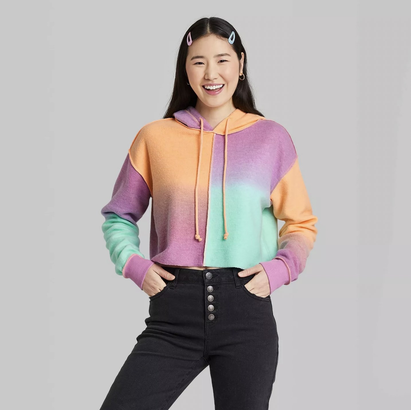 Model wearing the cropped pastel multicolor cropped hoodie with black high-waisted jeans