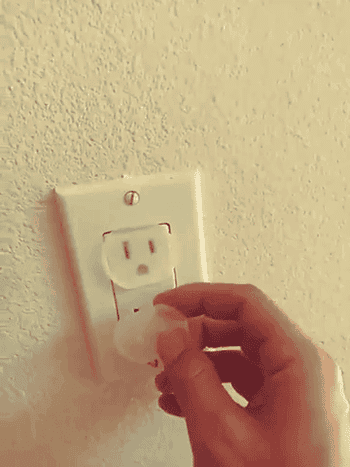 A person pushes the outlet cover into a wall outlet