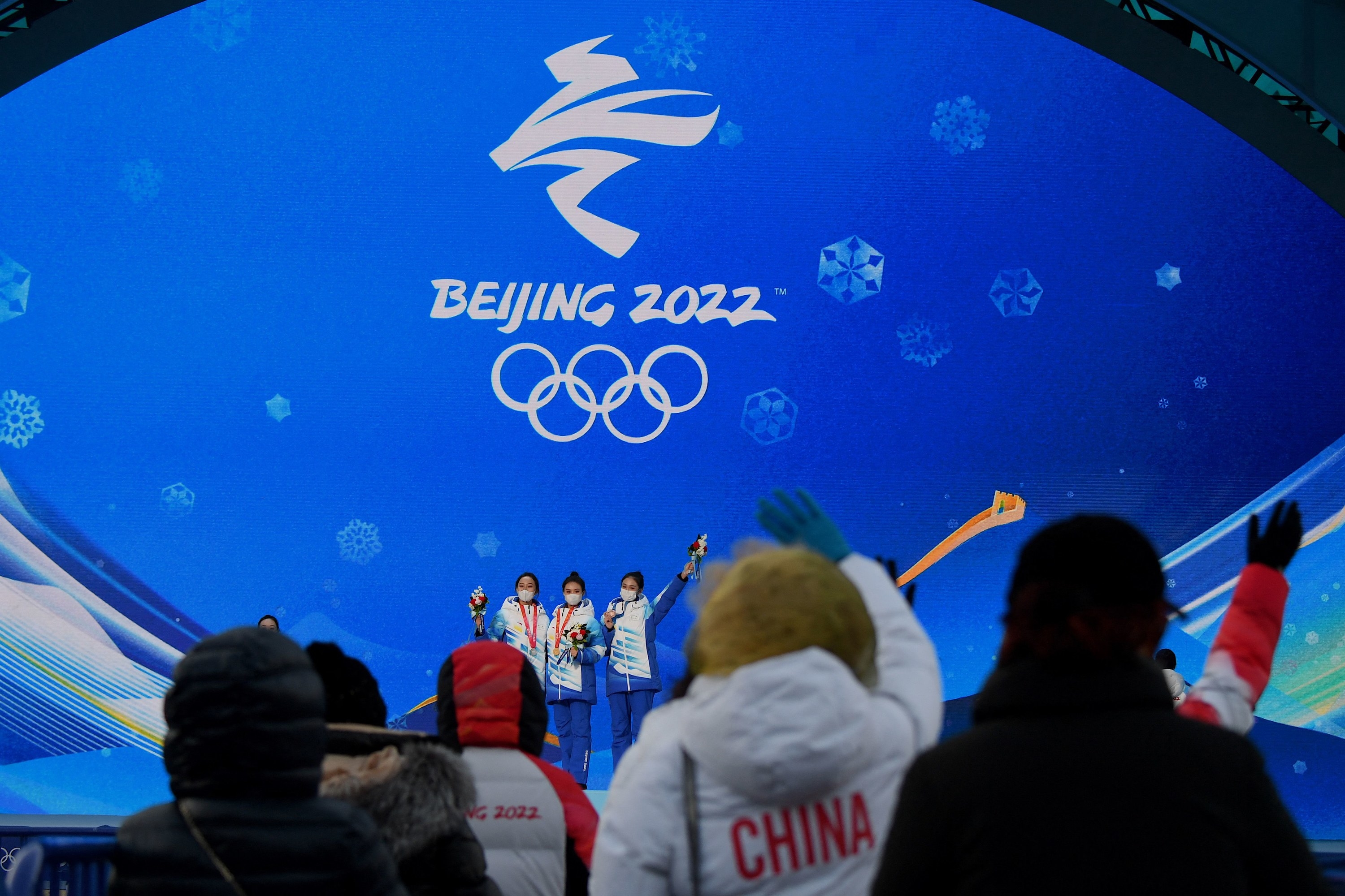 Grupo de atletas frente a una pantalla con el logo de Beijing 2022
